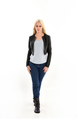 full length portrait of blonde girl wearing casual blue shirt and leather jacket. standing pose, isolated on white studio background.