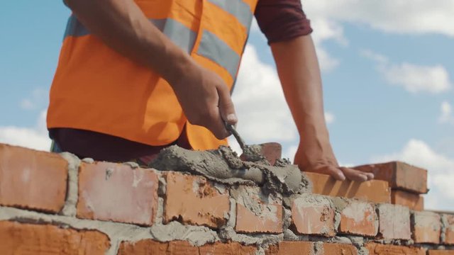 Close-up shot of Bricklayer builds wall