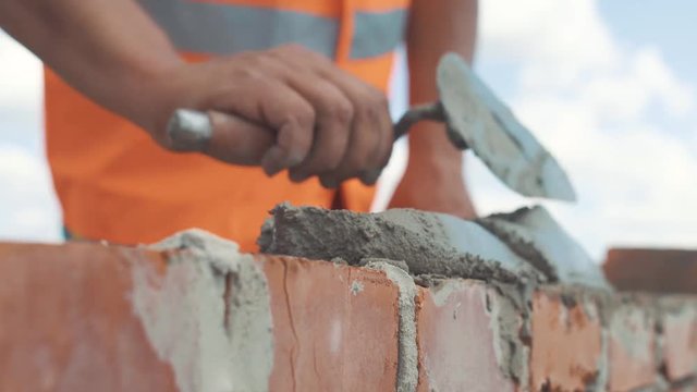 Handed shot of Bricklayer builds wall