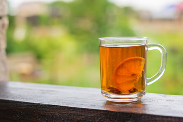 Tea mug with lemon on wooden rails on a summer day