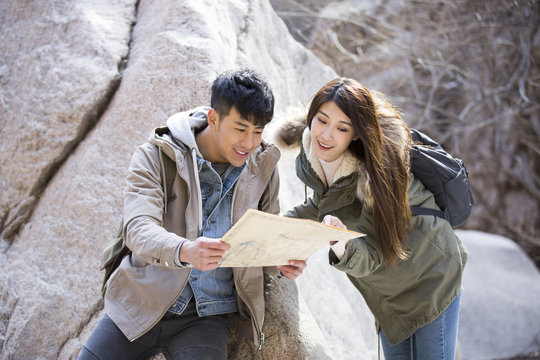 Happy young Chinese couple looking at a map outdoors