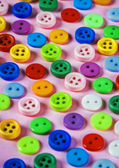 buttons of different colors on a pink background. Pastel shades