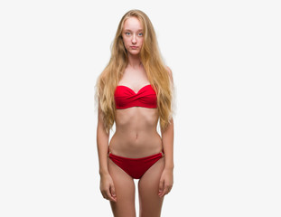 Blonde teenager woman wearing red bikini depressed and worry for distress, crying angry and afraid. Sad expression.