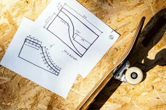 skateboard on a wooden background with plans for a miniramp in a skatepark