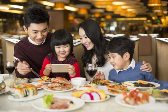 Cheerful young Chinese family having buffet dinner