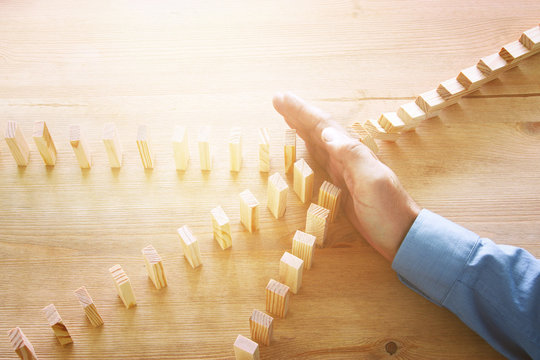 Image Of Male Hand Stopping The Domino Effect. Retro Style Image Executive And Risk Control Concept.