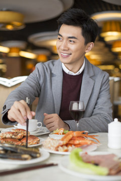 Cheerful young Chinese man having buffet dinner