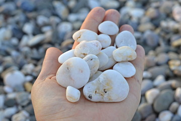 Hand holds a handful of stones sea