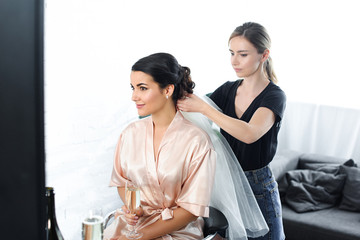 side view of focused hairstylist fixating veil on brides hair