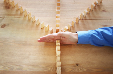 image of male hand stopping the domino effect. retro style image executive and risk control concept.