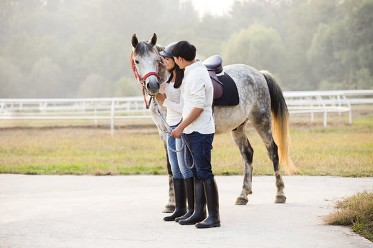 Cheerful young Chinese couple with horse 