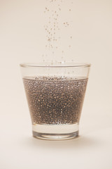Glass of water with cup of healthy chia seeds and spoon. Text space.