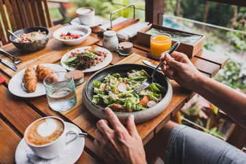 View from above on table with fresh breakfast. Man hands holding fork and knife
