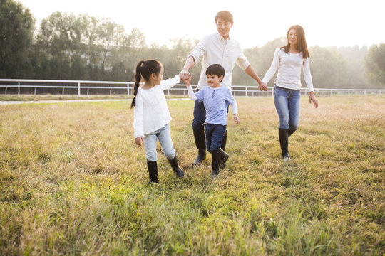 Cheerful young Chinese family walking on grassy field
