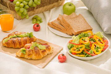 Healthy food and accessories outdoor summer or spring picnic, Picnic wicker basket with fresh fruit, bread and a glass of refreshing orange juice in the camping nature background.