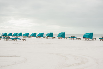 Sandy beach with white sand and rows of chaise lounges with canopies for relaxation. Coast of the Atlantic Ocean. Florida. USA. Mayer.
