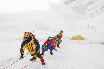 Roped team of mountaineers wearing oxygen masks