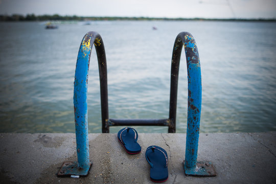 Pool ladder with selective focus in the lake with slippers without people.