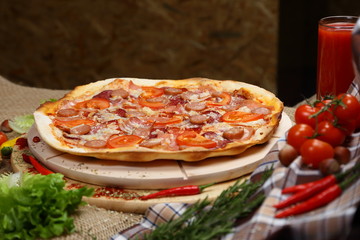 Pizza with sausages, tomato, smoked sausage, bacon, red pepper and cheese close-up