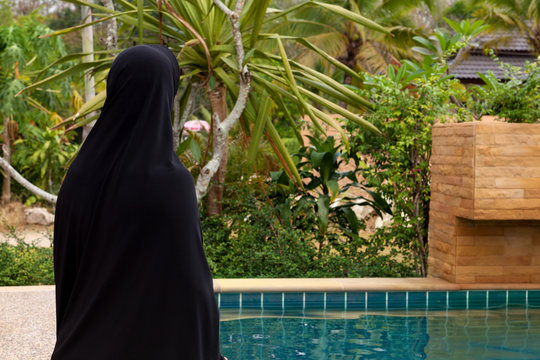 Arabic woman with headscarf at poolside.