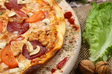 Pizza with mushrooms, tomato, smoked sausage, bacon, red pepper and cheese close-up