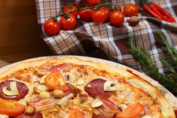 Pizza with mushrooms, tomato, smoked sausage, bacon, red pepper and cheese close-up