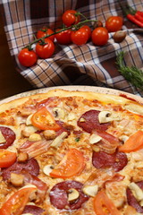 Pizza with mushrooms, tomato, smoked sausage, bacon, red pepper and cheese close-up
