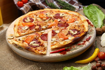 Pizza with mushrooms, tomato, smoked sausage, bacon, red pepper and cheese close-up