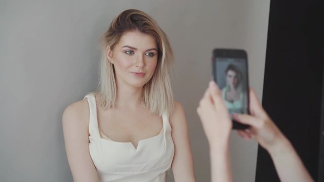 Makeup artist takes pictures of the model on the phone. Dark lips, gray background. Makeup