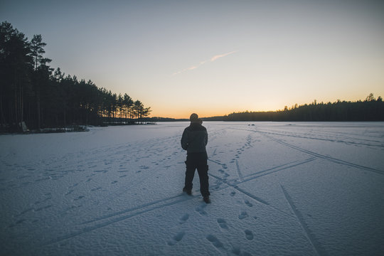 Sweden, Sodermanland, man walking on frozen lake Navsjon in winter