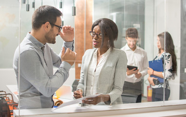 Businessman explaining something to his female colleague, gesturing with hands.