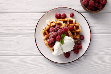 tasty belgian waffles with raspberries and ice cream on white wooden table