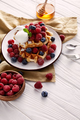 freshly baked belgian waffles with berries on white wooden table