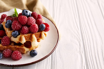 close-up shot of delicious belgian waffles on plate on white wooden table