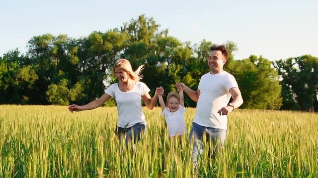 Happy family: Father, mother and son, running in the field dressed in white t-shirts