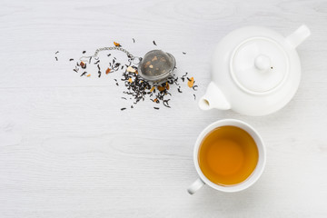 tasse de thé avec théière et infuseur fermé avec thé noir sur table