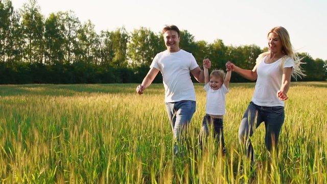 Happy family: Father, mother and son, running in the field dressed in white t-shirts