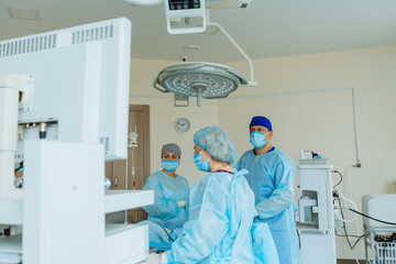 Surgeons team looks at monitors while preforming operation in hospital operating theater, male surgeon operating patient working with surgical laparoscopy instruments. Gynecology.