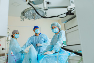 Surgeons team preforming operation uterus removal in hospital operating theater, male surgeon operating patient working with surgical laparoscopy instruments. Gynecology.