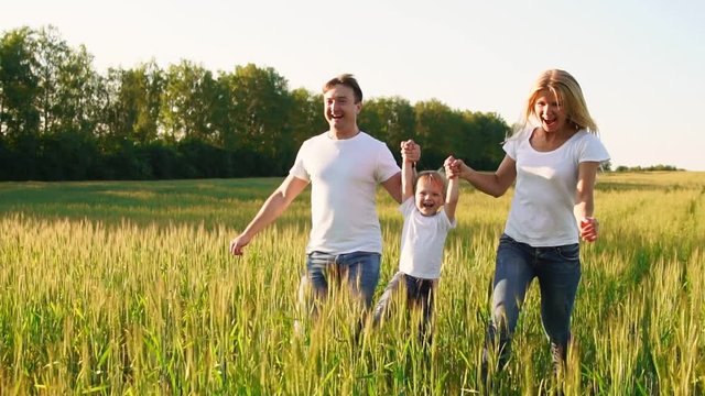 Happy family: Father, mother and son, running in the field dressed in white t-shirts