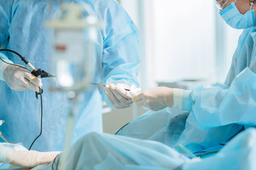 Close up of hands of surgeons team during operation uterus removal with surgical laparoscopy instruments. Gynecology.