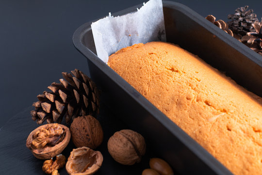 Fresh baked homemade pound, butter cake in loaf pan on slate stone plate decor by pinecorn and walnuts
