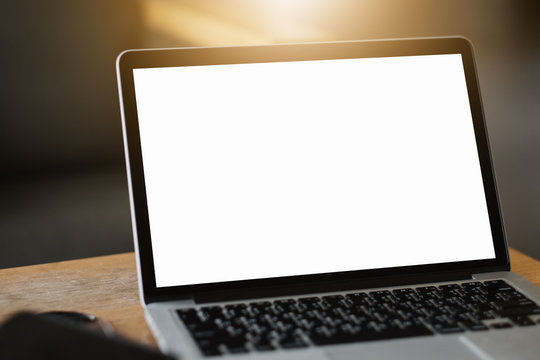 Mockup image of a businesswoman using laptop with blank white desktop screen with coffee cup on wooden table in cafe