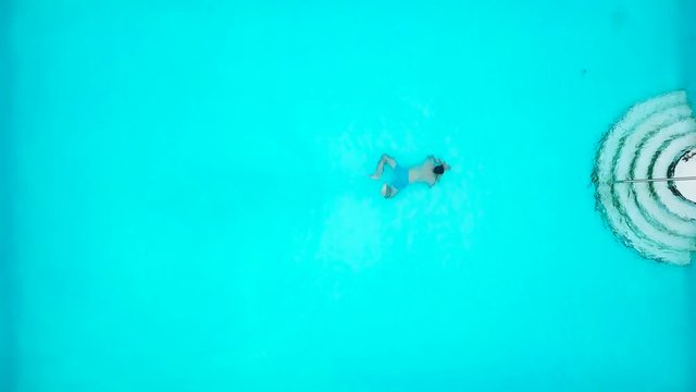 View from the top as a man jumping and dives into the pool and swims under the water