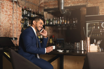 Cheerful business talking on phone in bar