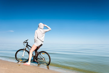 Young sporty lady resting from riding bicycle on the beach