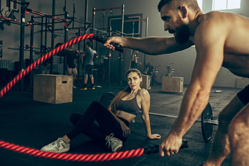 Men with battle rope battle ropes exercise in the fitness gym.