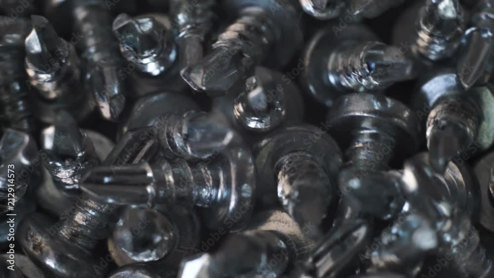 Aufkleber Macro screws rotating on a metal table and black background. Seamless loop.