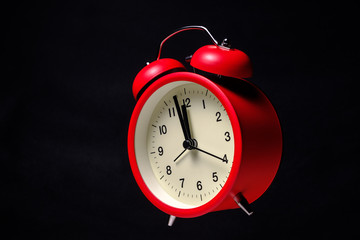 Red vintage alarm clock floating in the dark with blackboard background