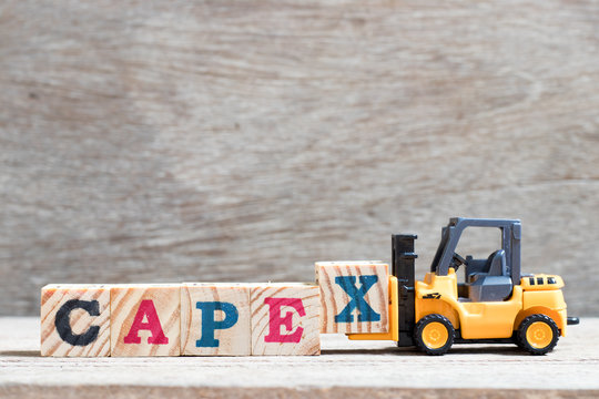 Toy forklift hold letter block x to complete word capex (abbreviation of capital expenditures) on wood background